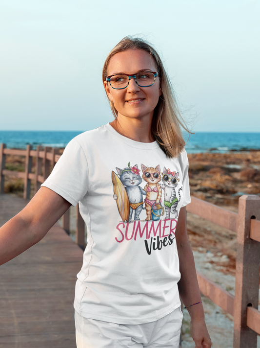 Blondes Mädchen mit Brille, im Hintergrund das Mee, trägt ein weißes Shirt mit Katzen-Motiv und Aufschrift "Summer Vibes"