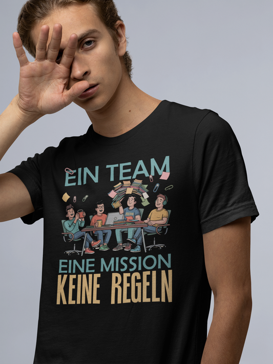 Junger Mann, Oberkörper, trögt ein schwarzes Shirt mit farbigen Comic-Print und der Aufschrift "Ein Team. Eine Mission. Keine Regeln."