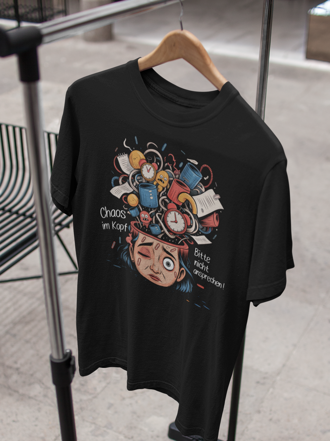 Schwarzes T-Shirt mit weißem Text „Chaos im Kopf – Bitte nicht ansprechen“, Motiv symbolisiert inneres Kopf-Chaos, hängend auf Kleiderständer