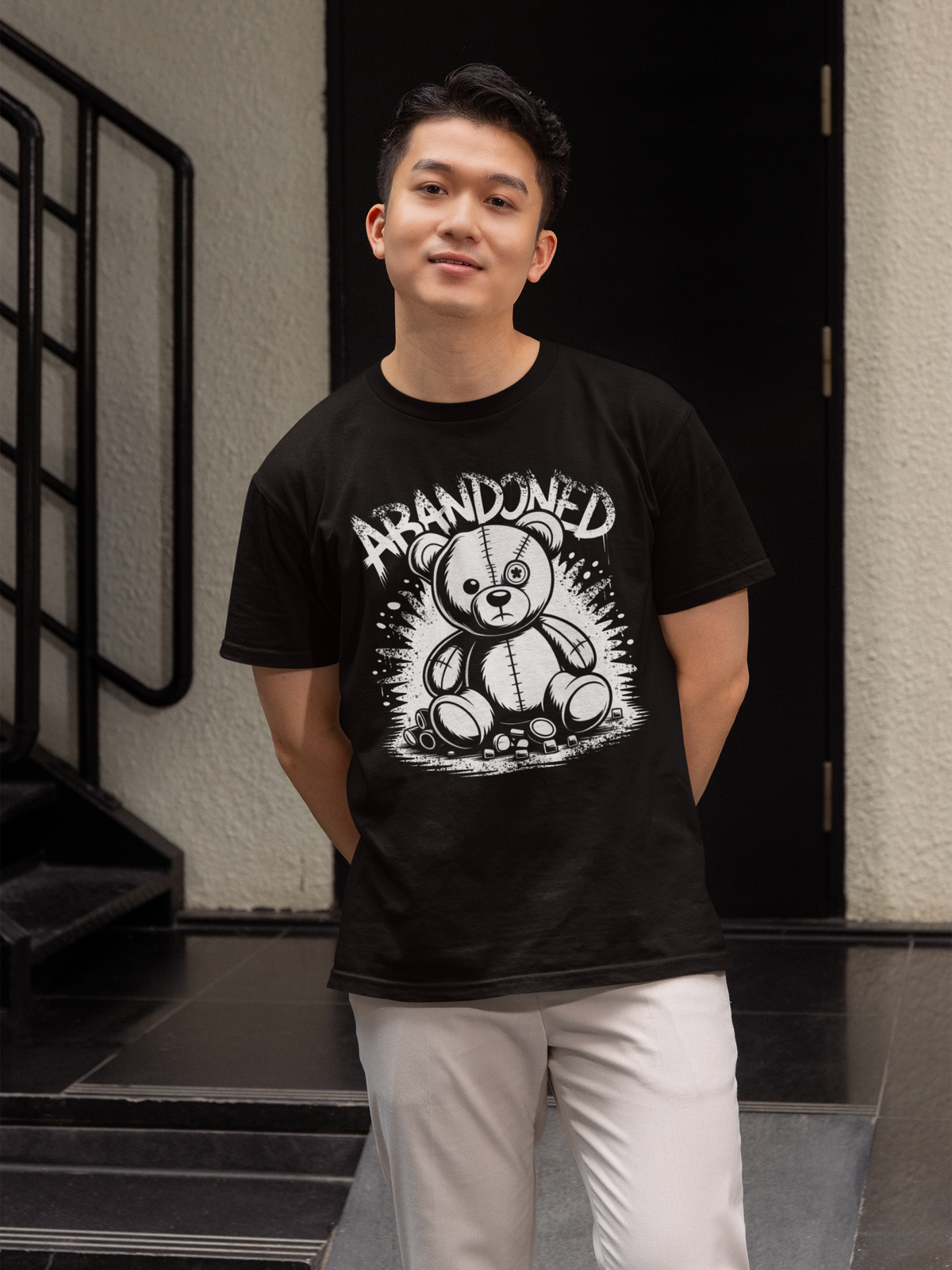 Junger Mann trägt schwarzes T-Shirt mit Abandoned Teddy Graffiti-Motiv (Oberkörperaufnahme)