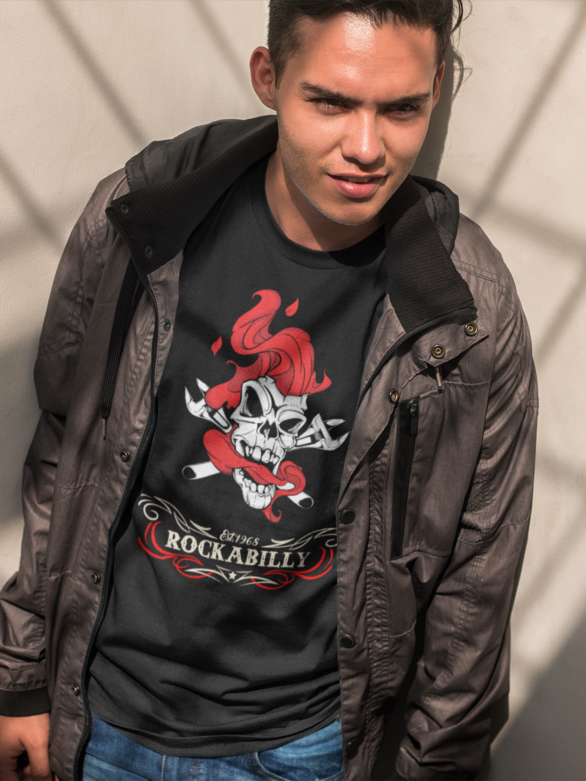 Junger Mann trägt eine graue Lederjacke offen und darunter ein schwarzes T-Shirt mit Smoking Skull und Schriftzug "Rockabilly", Oberkörperansicht