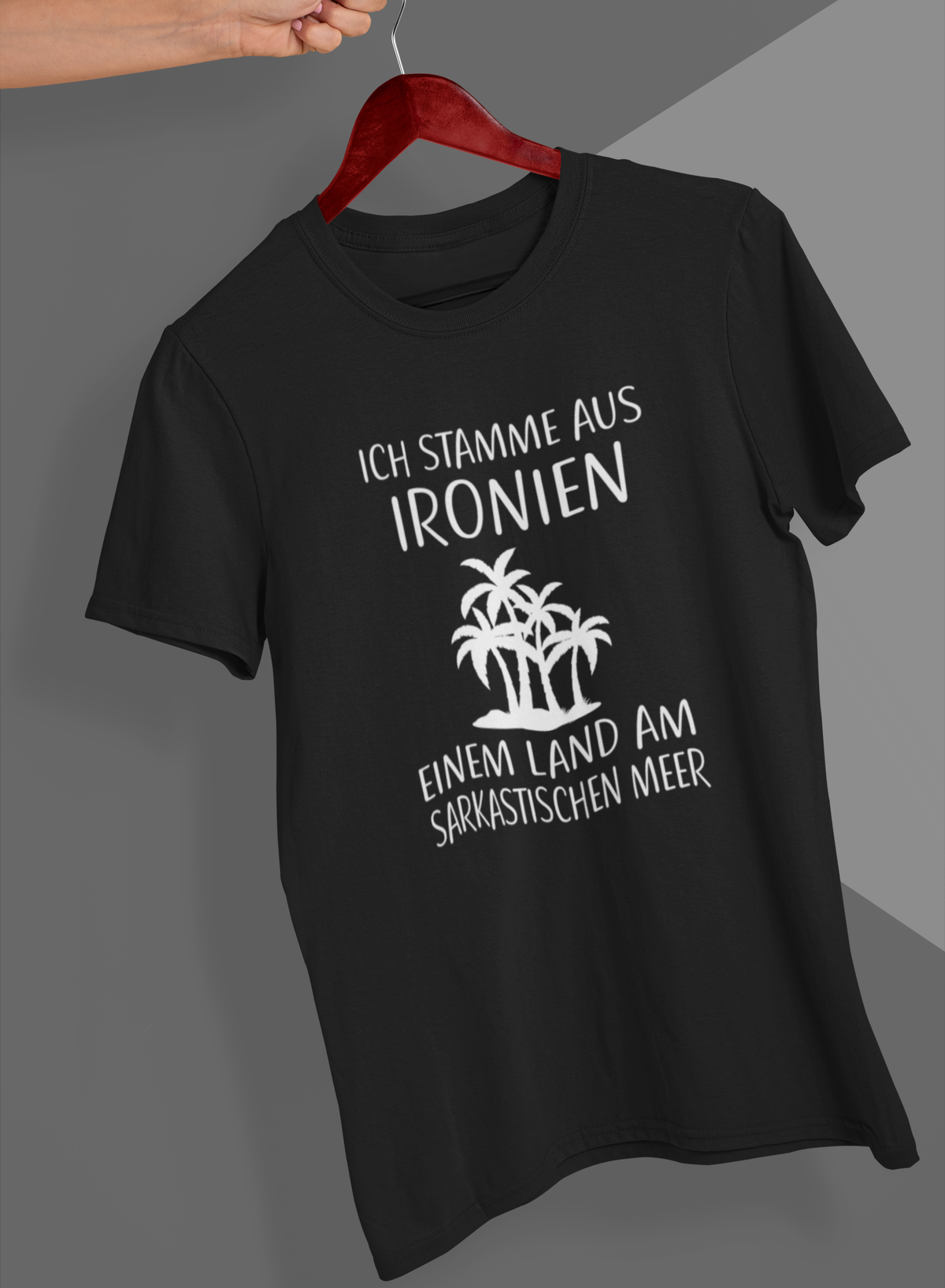 Schwarzes T-Shirt mit weißem Text „Ich stamme aus Ironien, einem Land am sarkastischen Meer“ auf Kleiderbügel