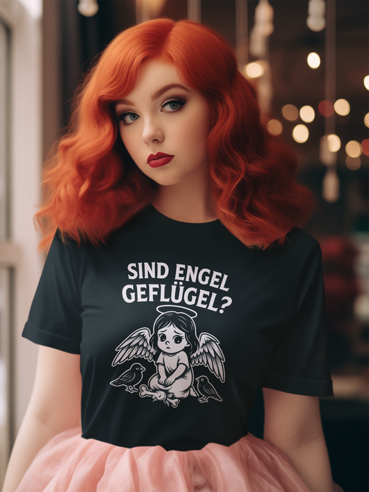 Mädchen mit rotem Haar trägt schwarzes T-Shirt mit frechem Engel im Gothic-Comic-Stil und Schriftzug „Sind Engel Geflügel?“.