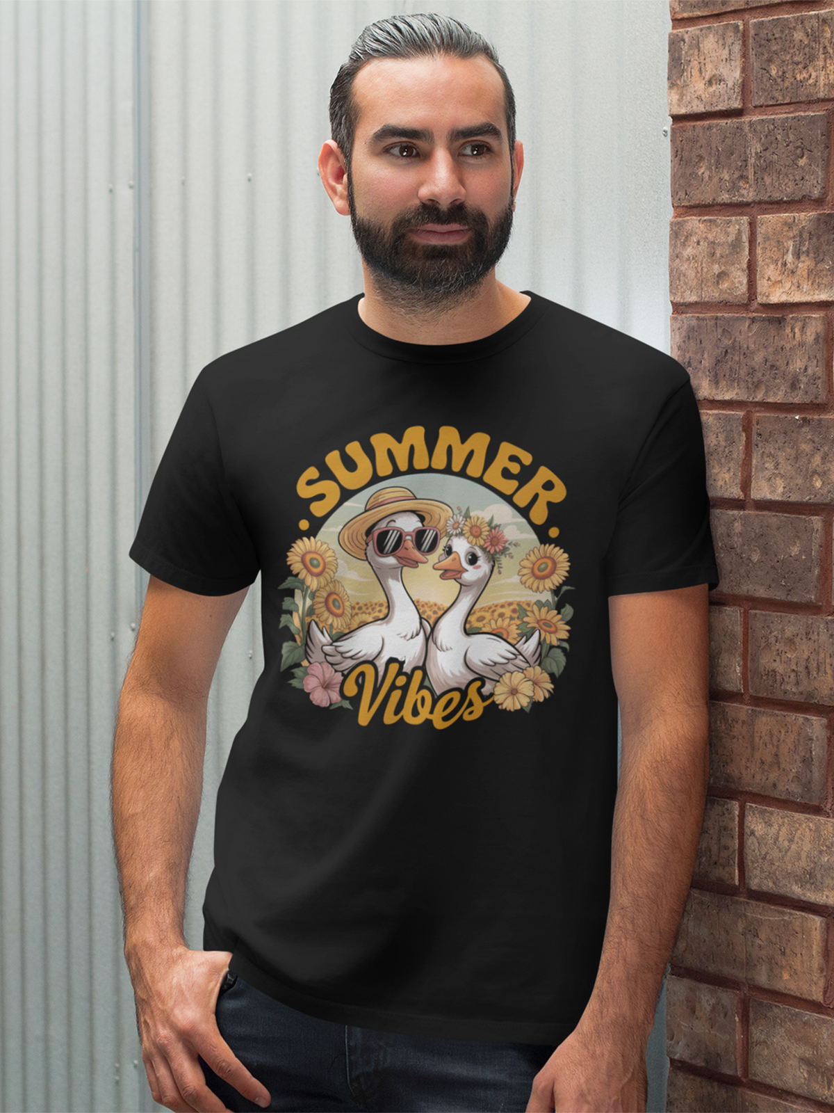 Mann mit Bart ist an eine Mauer angelehnt. Er trägt ein schwarzes Shirt mit zwei Gänsen und Schriftzug "Summer Vibes"