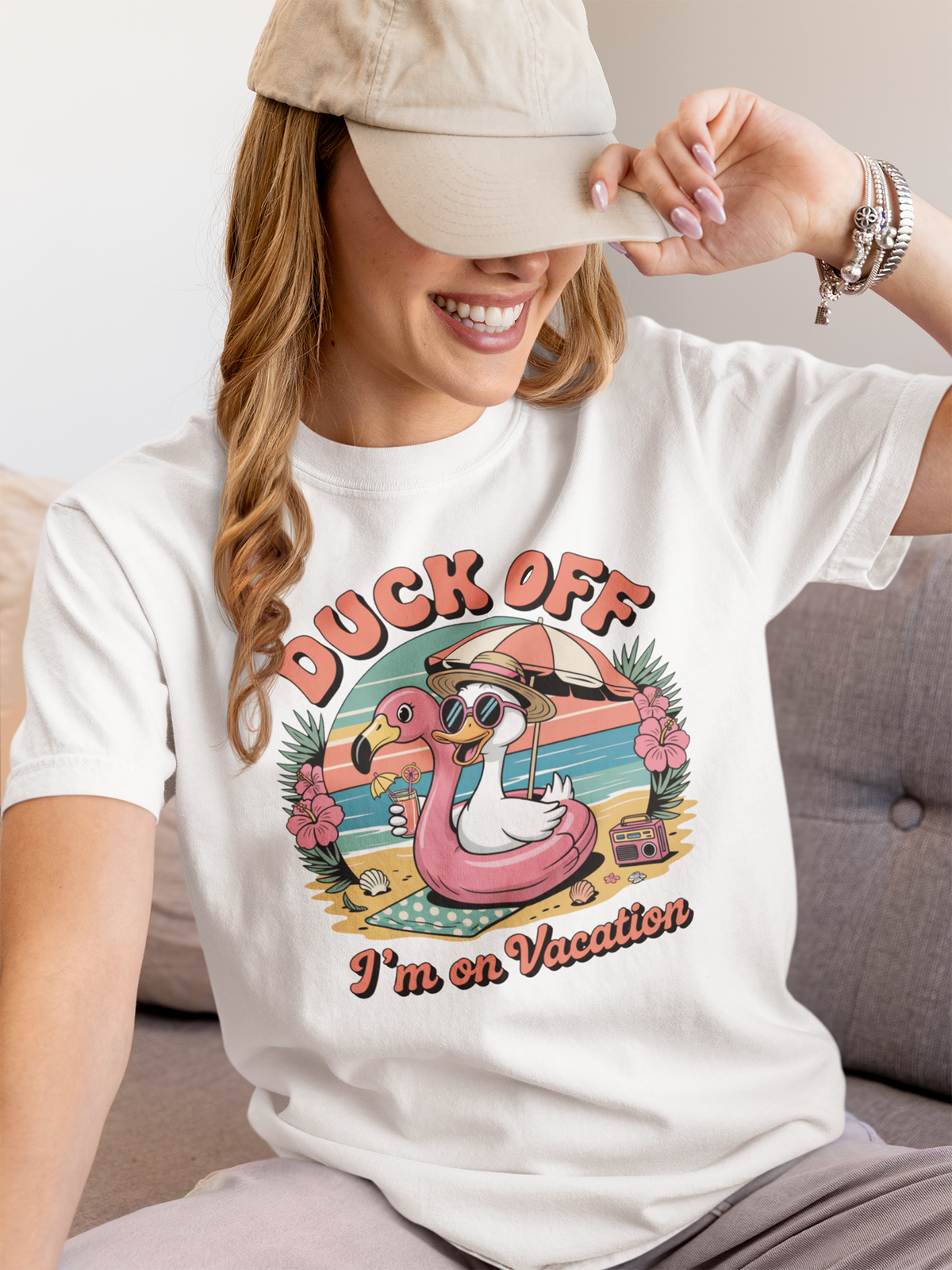 Frau, sitzen, mit Kappe, trägt weißes Shirt mit Enten-Flamingo-Motiv und Aufdruck "Duck Off"
