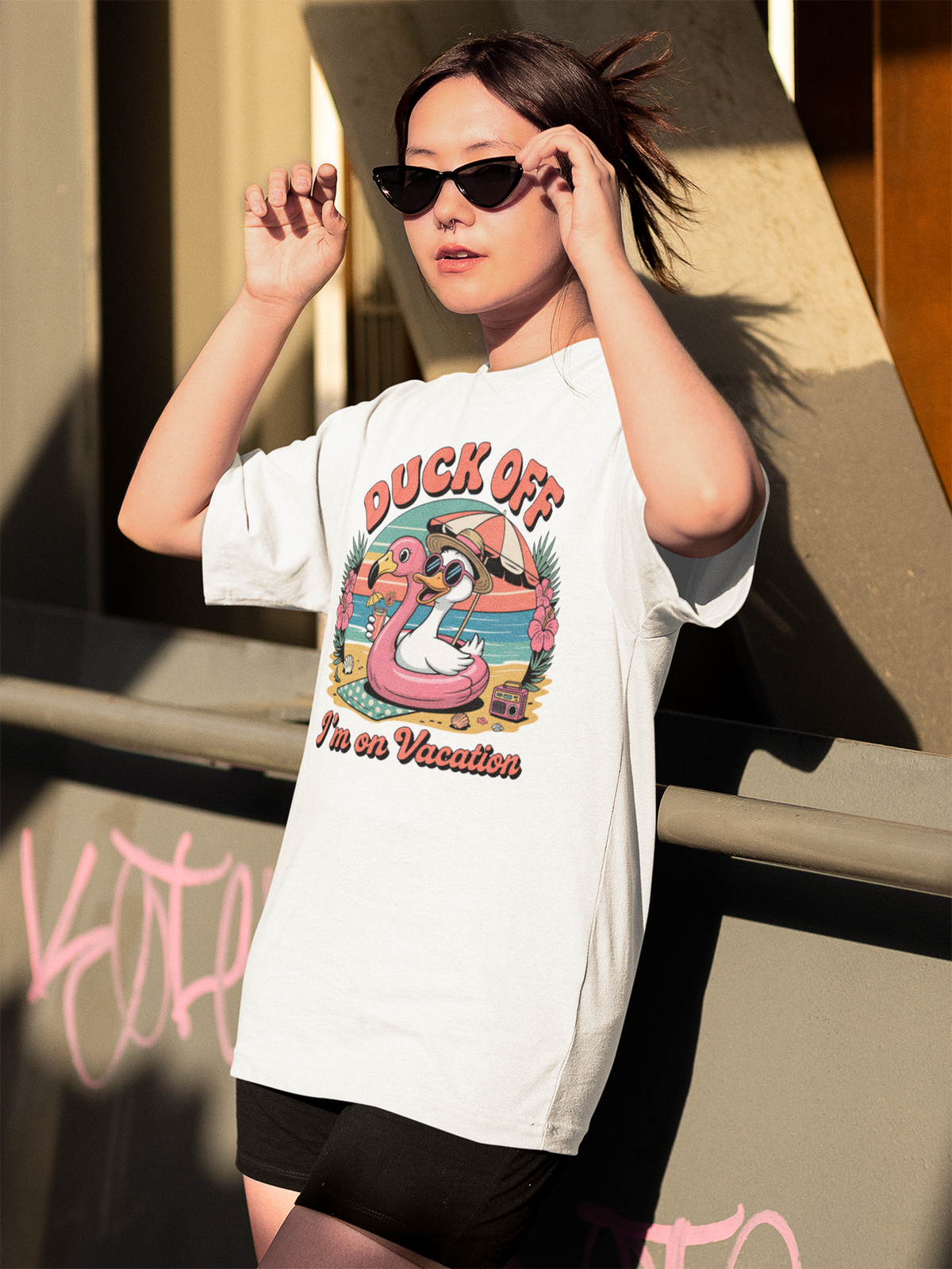 Mädchen mit Sonnenbrille trägt ein weißes Shirt mit Enten-Flamingo-Motiv und Aufdruck "Duck Off"