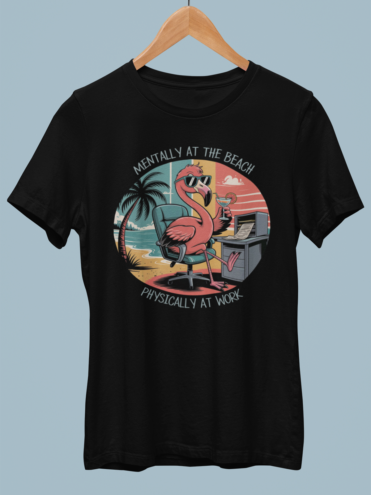 Schwarzes Shirt mit Flamingo-Motiv hängt auf Holzkleiderbügel.