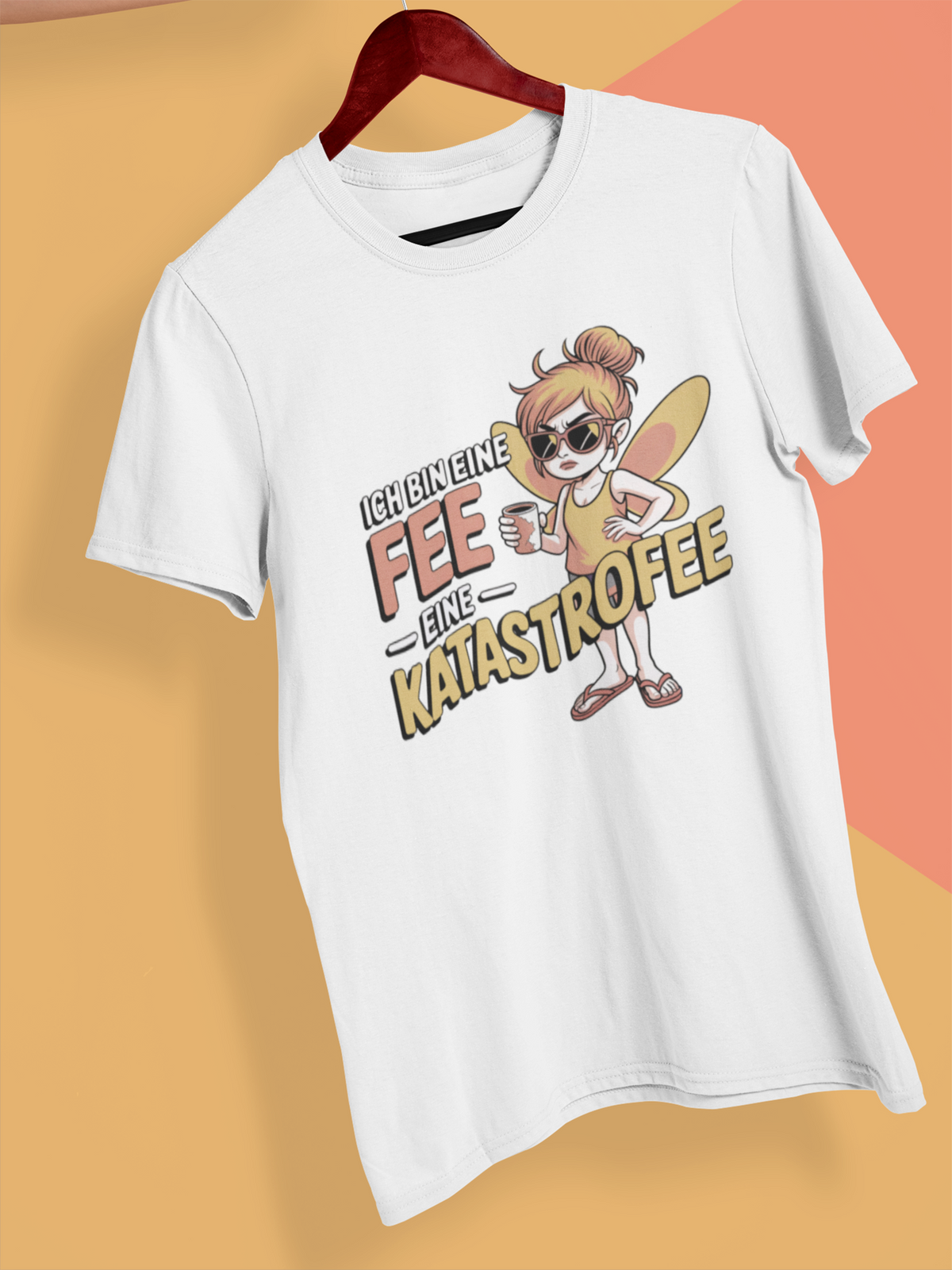 Weißes T-Shirt mit Text: „Ich bin eine Fee. Eine Katastrofee.“ auf Holzkleiderbügel