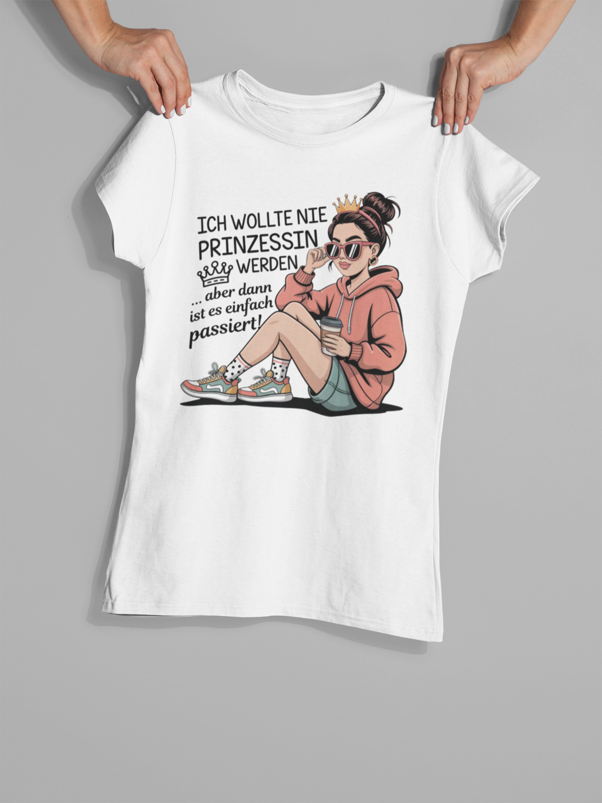 Hände halten ein weißes Shirt mit Comic-Figur-Print und Aufdruck: "Ich wollte nie eine Prinzessin werden"