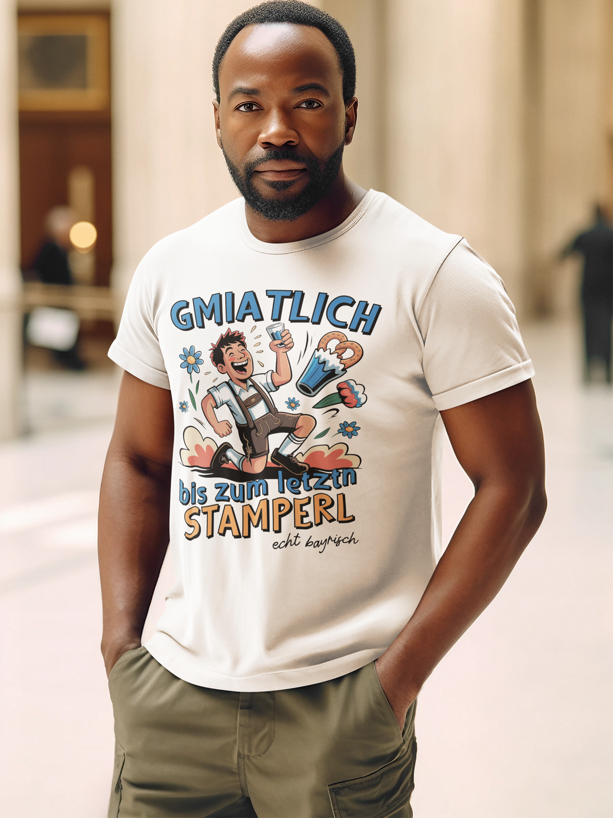 Schwarzer Mann mit Bart trägt weißes T-Shirt mit bayerischem Comic-Motiv und Spruch „Gmiatlich bis zum letztn Stamperl“, Oberkörperansicht