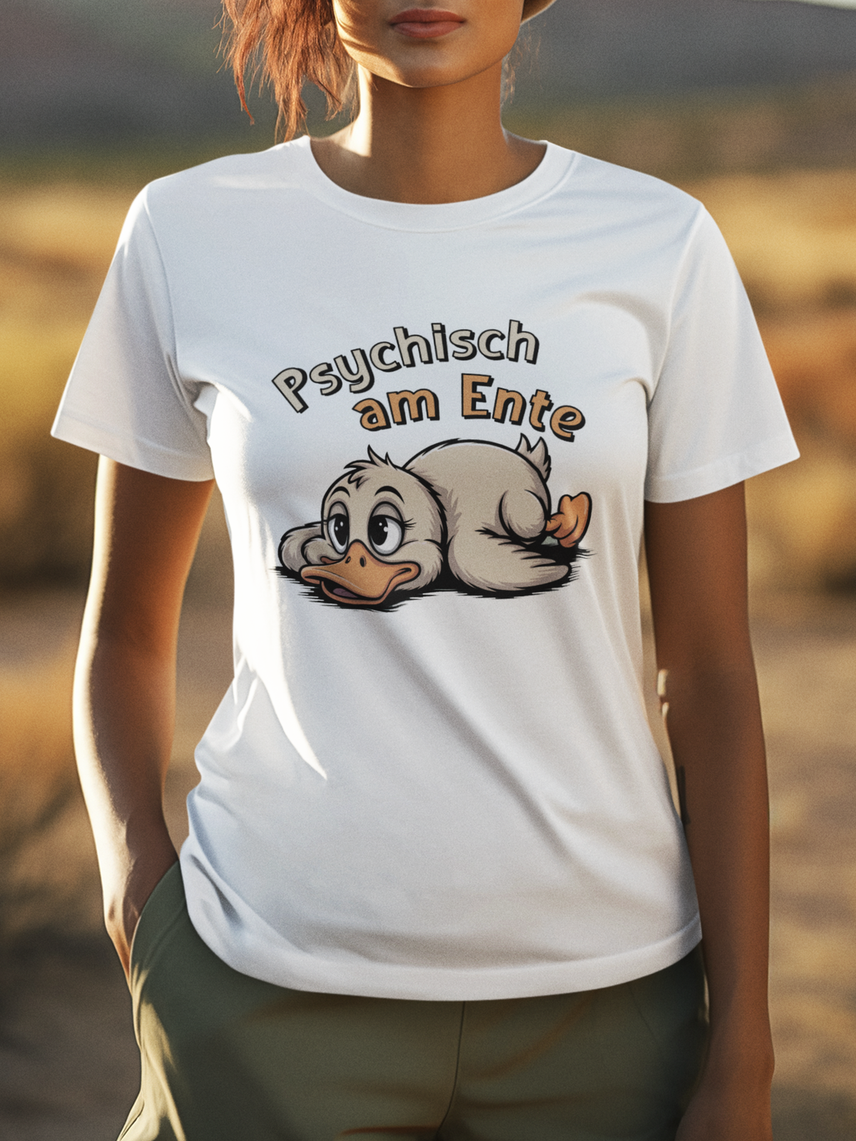 Junge Frau trägt weißes T-Shirt mit Ente und dem Text „Psychisch am Ente“ (Oberkörperaufnahme). Verschwommener Hintergrund