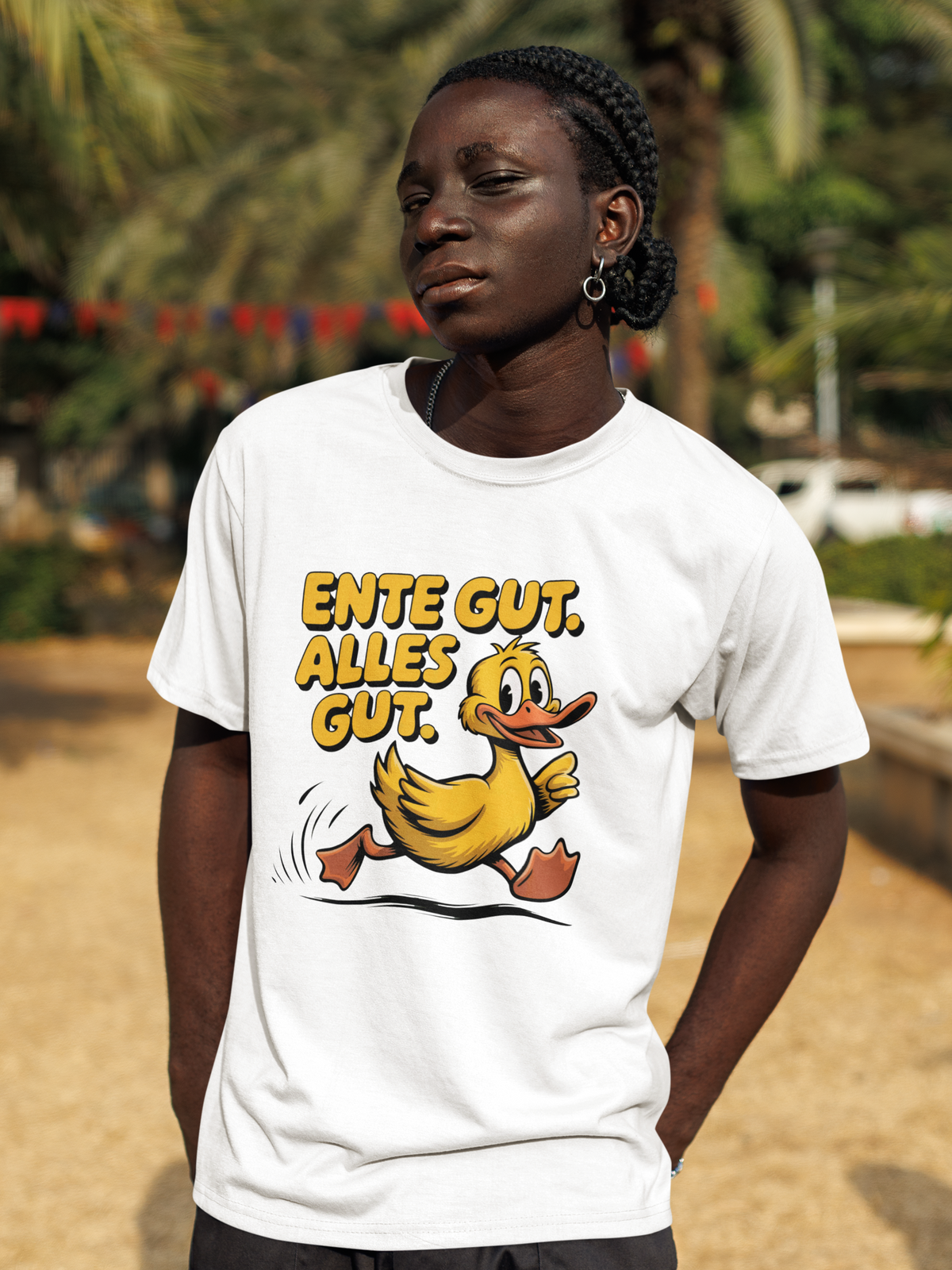 Junger schwarzer Mann trägt weißes T-Shirt mit Ente und dem Spruch „Ente gut, alles gut“ (Oberkörperaufnahme)