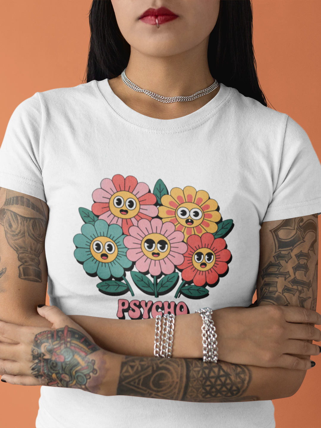 Junge Frau mit tättowierten Armen trägt weißes Shirt mit psychedelischen Blumen und „Psycho Flora Club“-Text (Oberkörper)