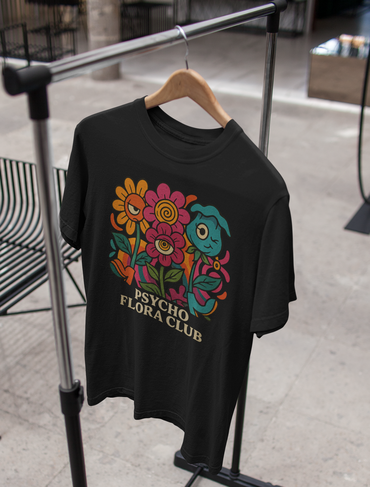 Schwarzes T-Shirt mit buntem Retro-Blumenmotiv und Schriftzug „Psycho Flora Club“ auf Kleiderständer