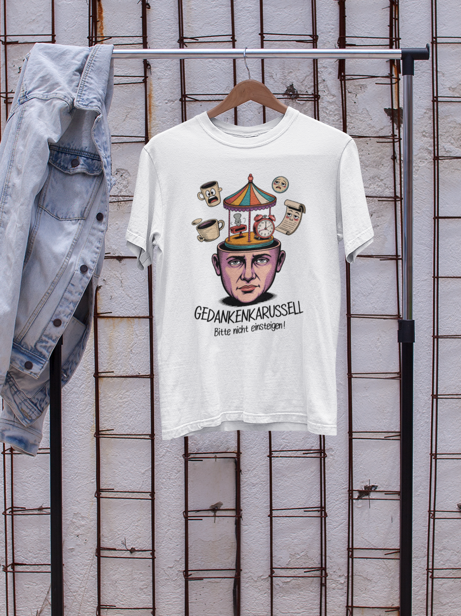 Weißes T-Shirt mit Text „Gedankenkarussell – Bitte nicht einsteigen“ und Karssell-Kopf-Motiv. Auf Kleiderständer. Links hängt eine Jeansjacke