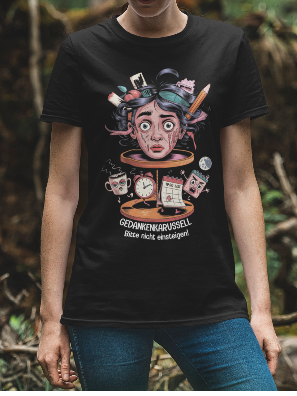 Oberkörperansicht einer jungen Frau mit schwarzem T-Shirt mit surrealistischem Kopf-Karussell-Motiv und weißem Text „Gedankenkarussell – Bitte nicht einsteigen“