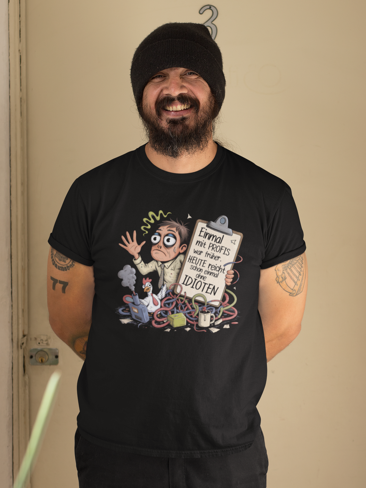 Mann mit Bart und Mütze trägt schwarzes Shirt mit dem Spruch „Einmal mit Profis war früher – Heute reicht schon einmal ohne Idioten“ (Oberkörperaufnahme)