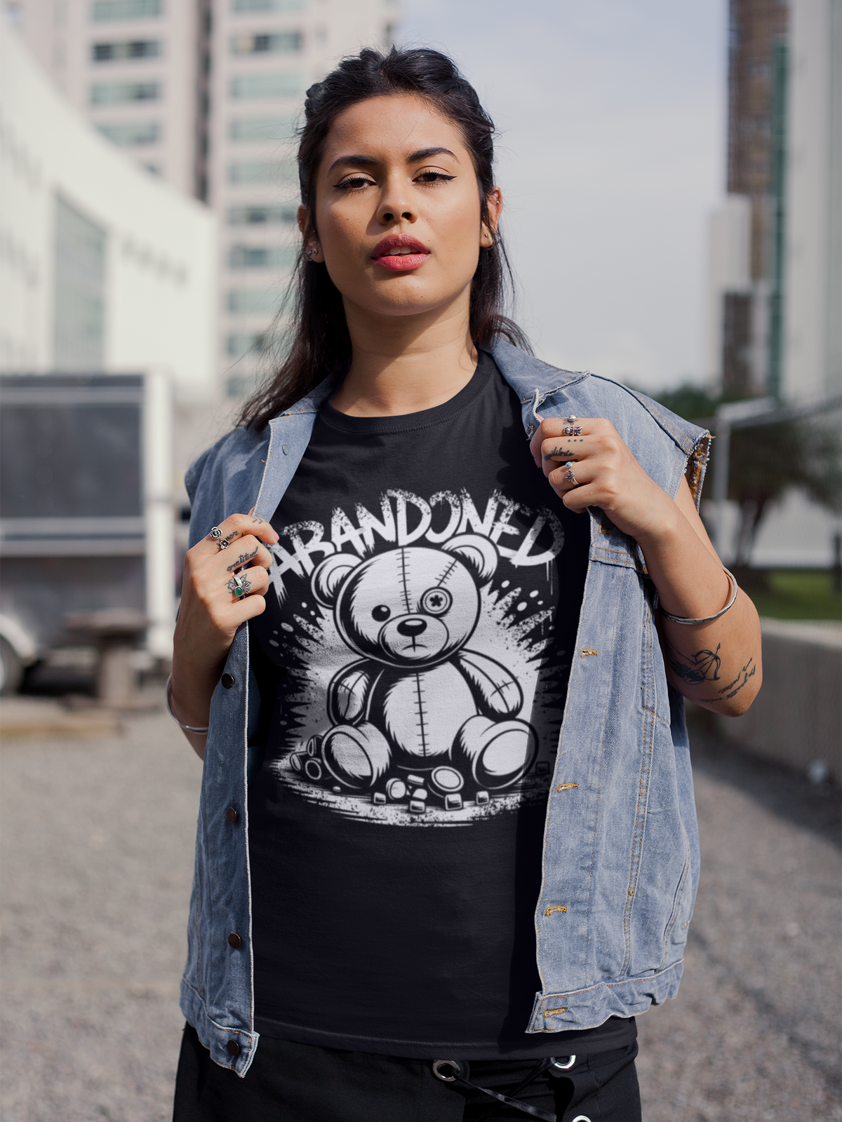 Frau mit Jeansjacke, darunter trägt sie ein schwarzes T-Shirt mit Abandoned Teddy Graffiti-Motiv (Oberkörperaufnahme)