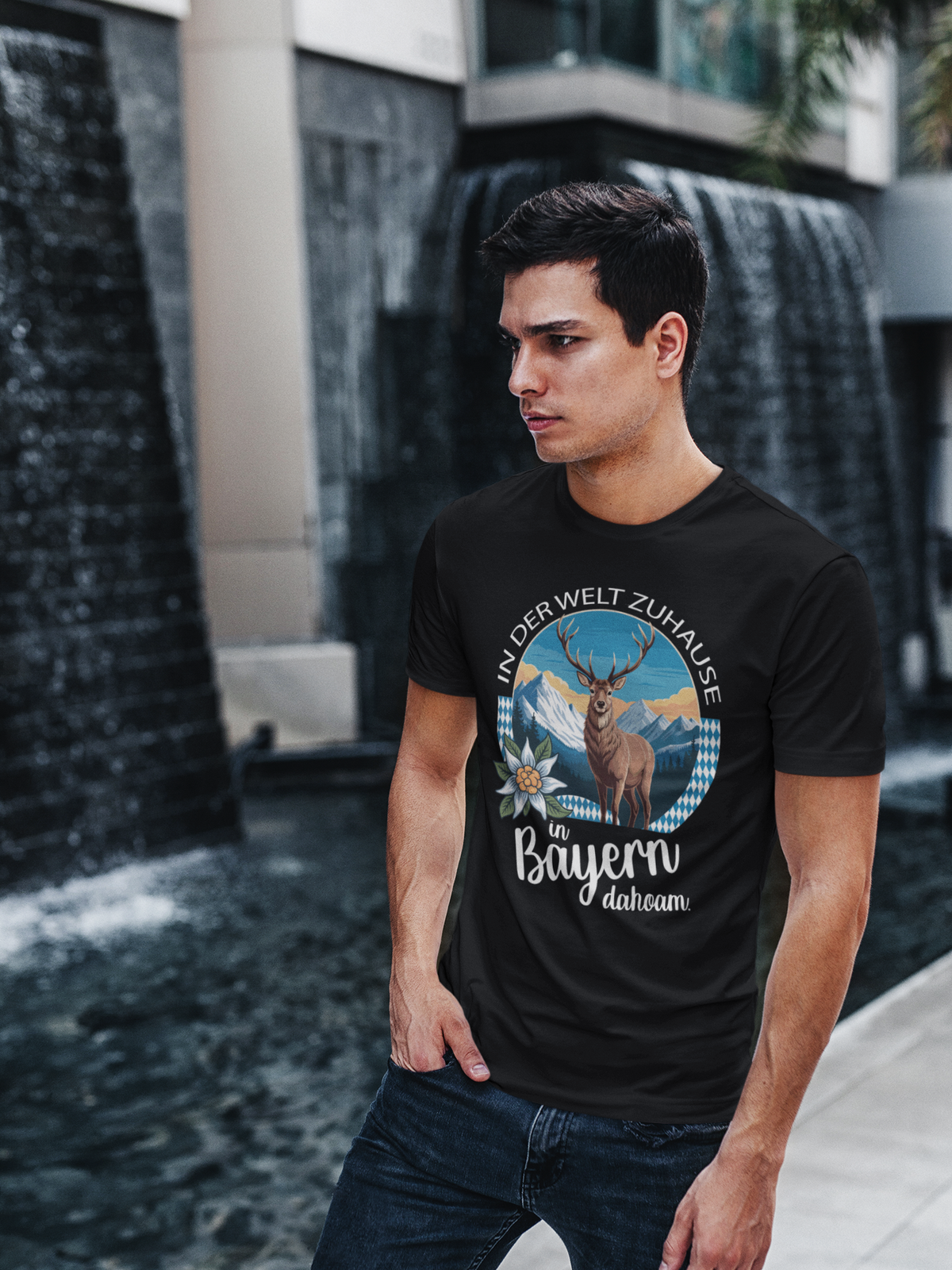 Mann trägt schwarzes T-Shirt mit Motiv „In der Welt zuhause. In Bayern dahoam“ (Oberkörper)