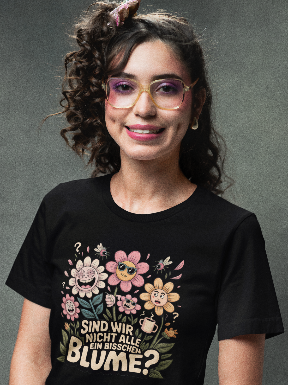 Frau trägt schwarzes Shirt mit farbigem Motiv aus schrägen Blumen und Text (Oberkörperaufnahme)