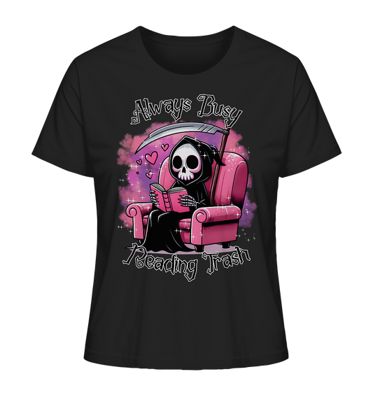 Schwarzes T-Shirt mit Motiv: Lesender süßer Sensemann auf rosa Sessel. Comic-Stil. Schriftzug: Always Busy Reading Trash.