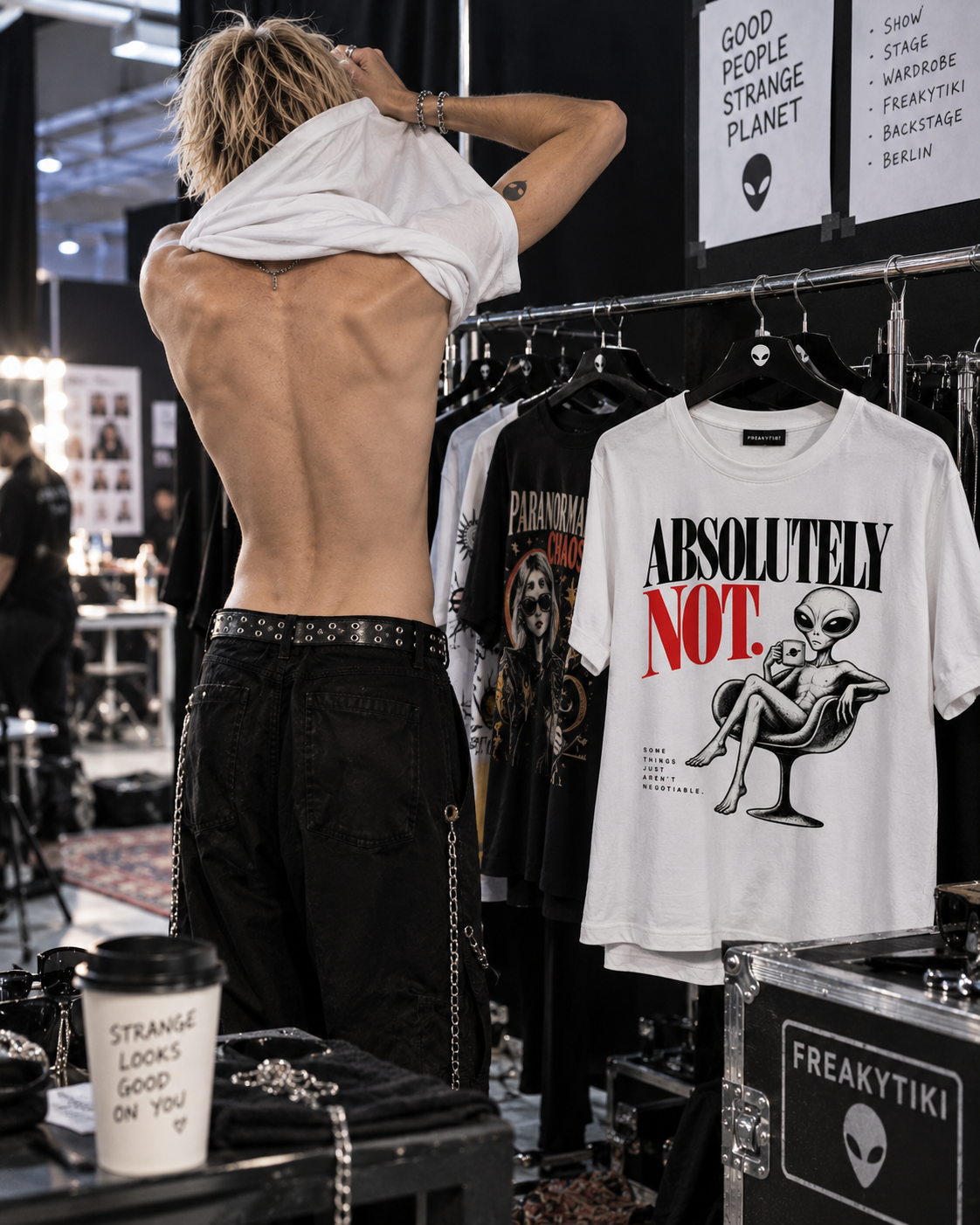 T-Shirt auf einem Kleiderständer hinter dem Laufsteg mit Absolutely Not – schwarze und rote Serifenschrift mit Alien im Sessel