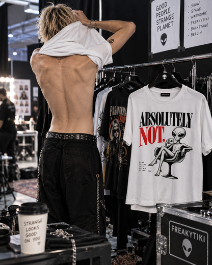 T-Shirt auf einem Kleiderständer hinter dem Laufsteg mit Absolutely Not – schwarze und rote Serifenschrift mit Alien im Sessel