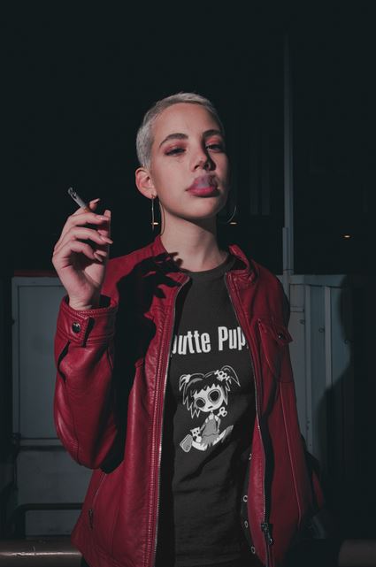 Frau mit roter Lederjacke trägt chwarzes Shirt mit kaputter Gothic-Puppe und Schriftzug Kaputte Puppe
